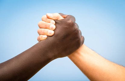 Black and white human hands in a modern handshake to show each other friendship and respect - Arm wrestling against racism
